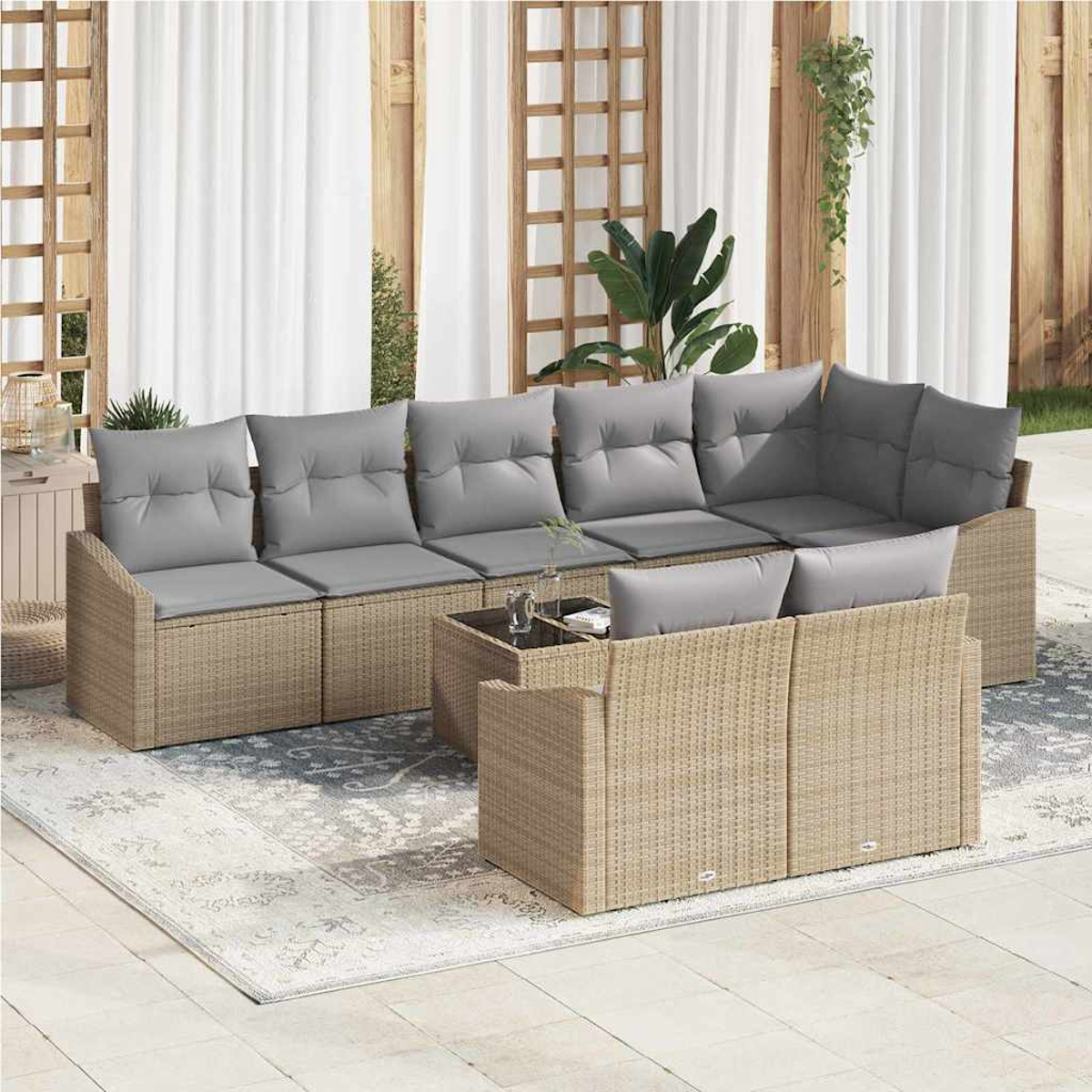 Juego de muebles de patio. Sofá de mimbre beige con cojines grises, mesa de centro y alfombra en un patio, con cortinas blancas.