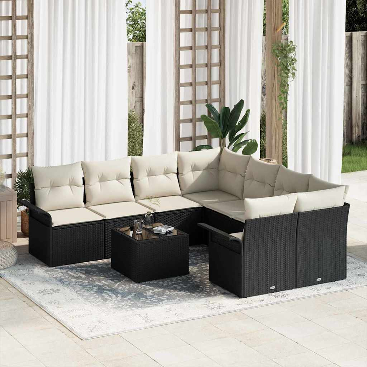 Outdoor-Ecksofa mit cremefarbenen Kissen, schwarzem Webrahmen, auf einem gemusterten Teppich, in der Nähe von weißen Vorhängen und Holzspalier.