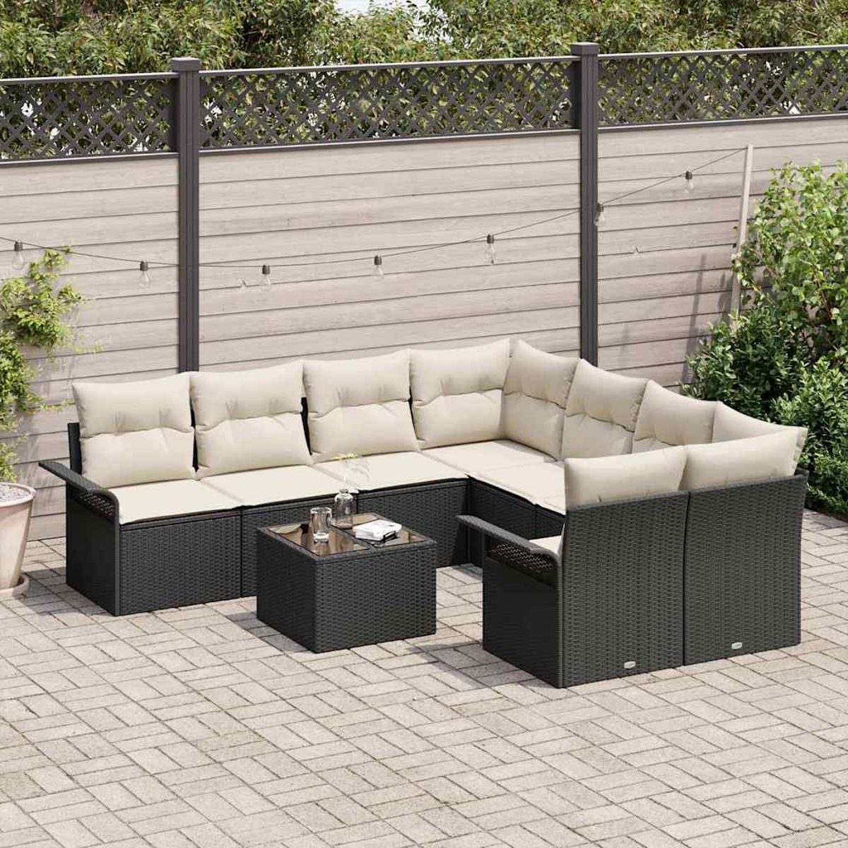 Outdoor-Terrassenset mit schwarzen Korbmöbeln, beigen Kissen und einem Couchtisch mit Glasplatte auf einer Ziegelterrasse. Im Hintergrund ist ein Zaun.