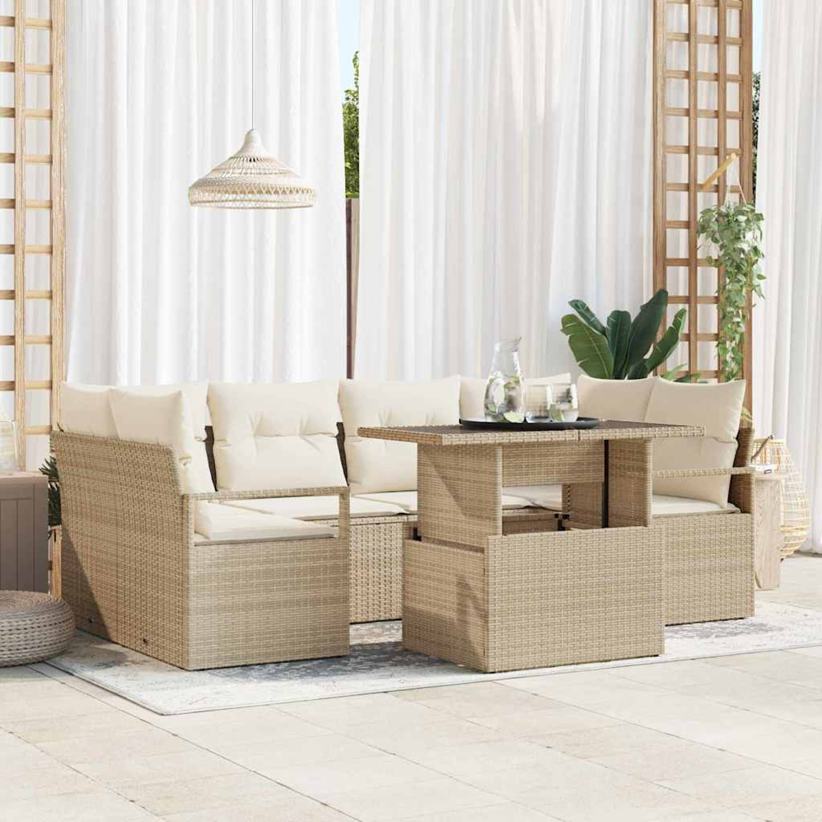 Garten-Set mit beigen Korbmöbeln, cremefarbenen Kissen und einem Tisch mit Hubfunktion. Weiße Vorhänge und eine Hängelampe im Hintergrund.