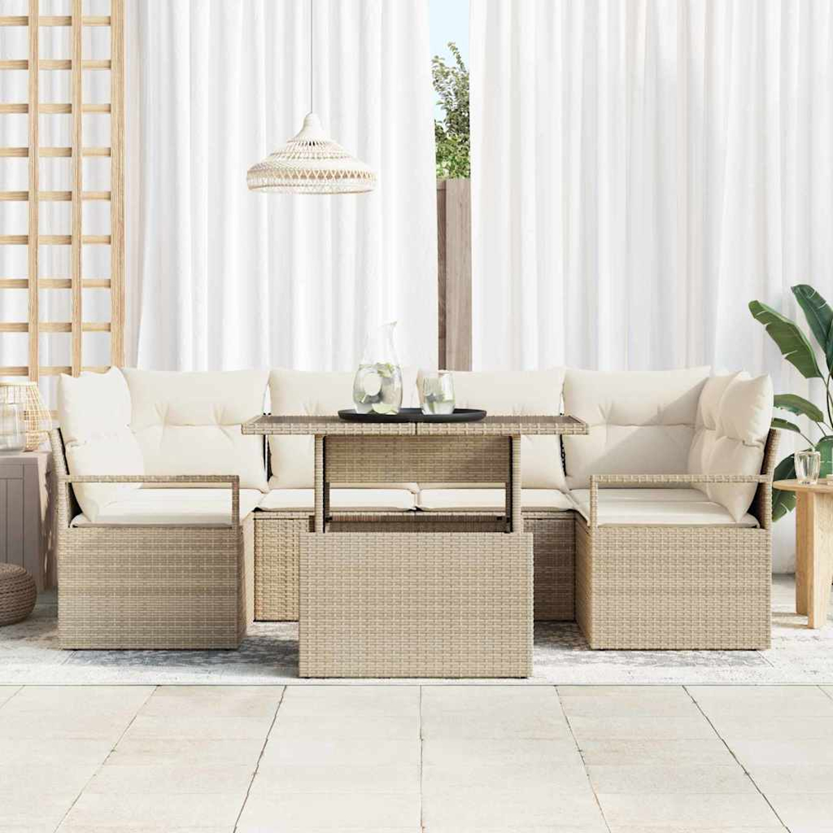 Gartenmöbel-Set aus Rattan mit beigen Kissen, Glastisch, weißen Vorhängen im Hintergrund und einer Hängeleuchte.