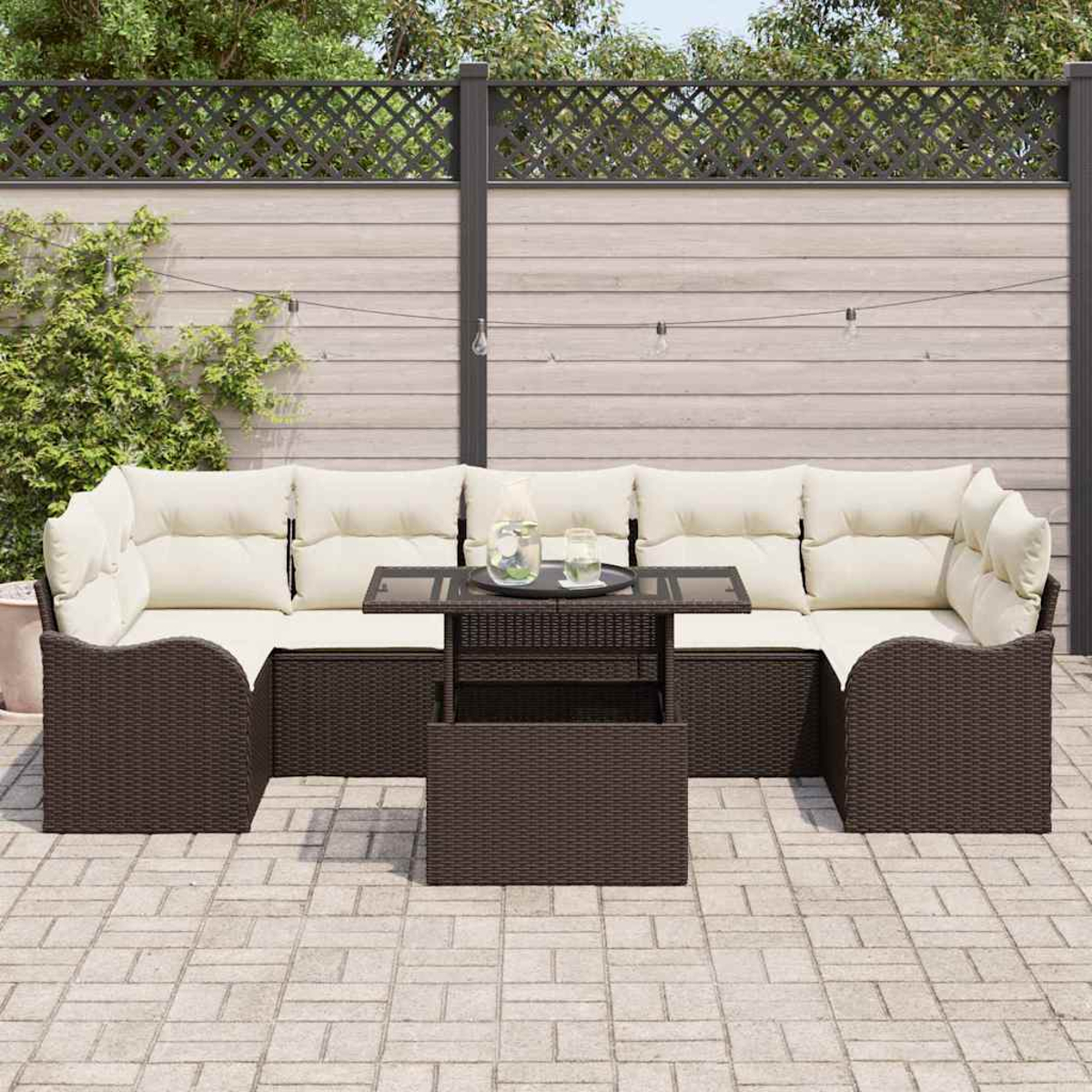 Eine Terrassengarnitur mit braunen Webmöbeln und cremefarbenen Kissen. Vor dem Sofa steht ein Glastisch mit Getränken. Holzzaun im Hintergrund.
