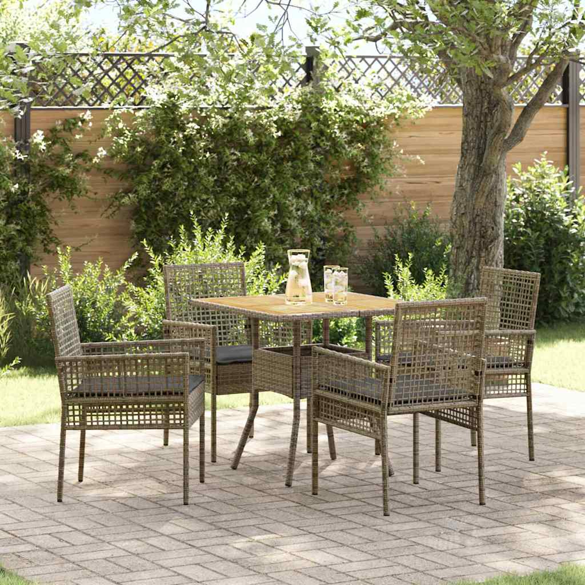 Eine Gartenszene mit Tisch und vier Stühlen. Eine Karaffe und Gläser stehen auf dem Tisch. Grünes Laub und ein Baum im Hintergrund.