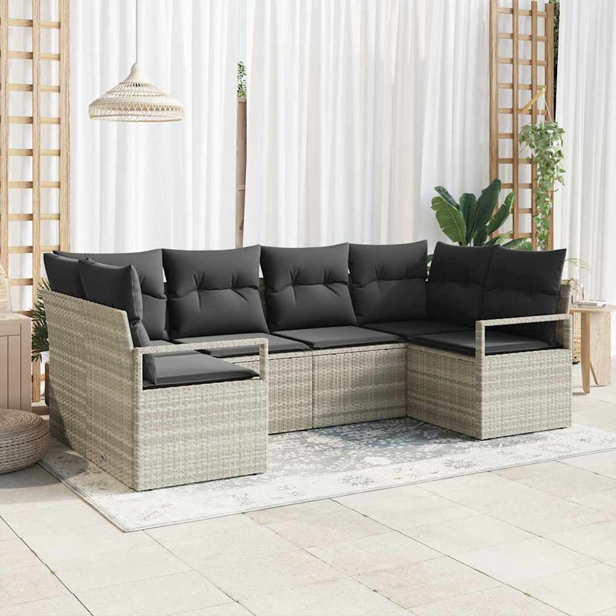 Ein Ecksofa mit grauen Kissen im Freien steht auf einem Teppich. Weiße Vorhänge und eine Hängelampe sind im Hintergrund.