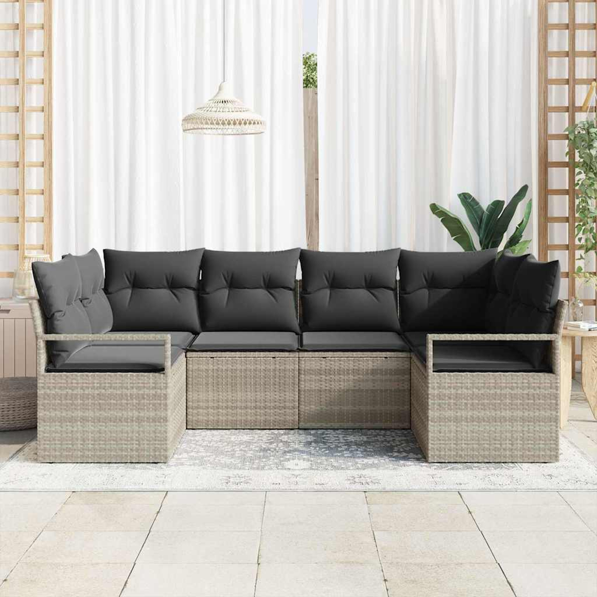 Outdoor-Ecksofa mit grauen Kissen. Beiger Korbrahmen. Weiße Vorhänge im Hintergrund. Eine Pendelleuchte hängt darüber.
