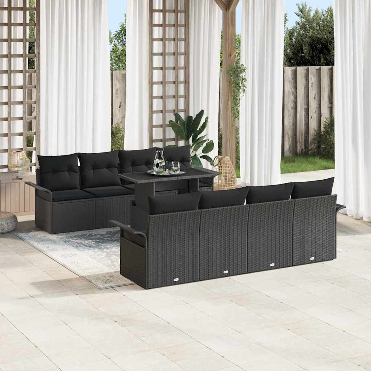 Gartenmöbel-Set mit schwarzen Kissen, Tisch und weißen Vorhängen im Hintergrund. Die Szene ist hell und luftig.