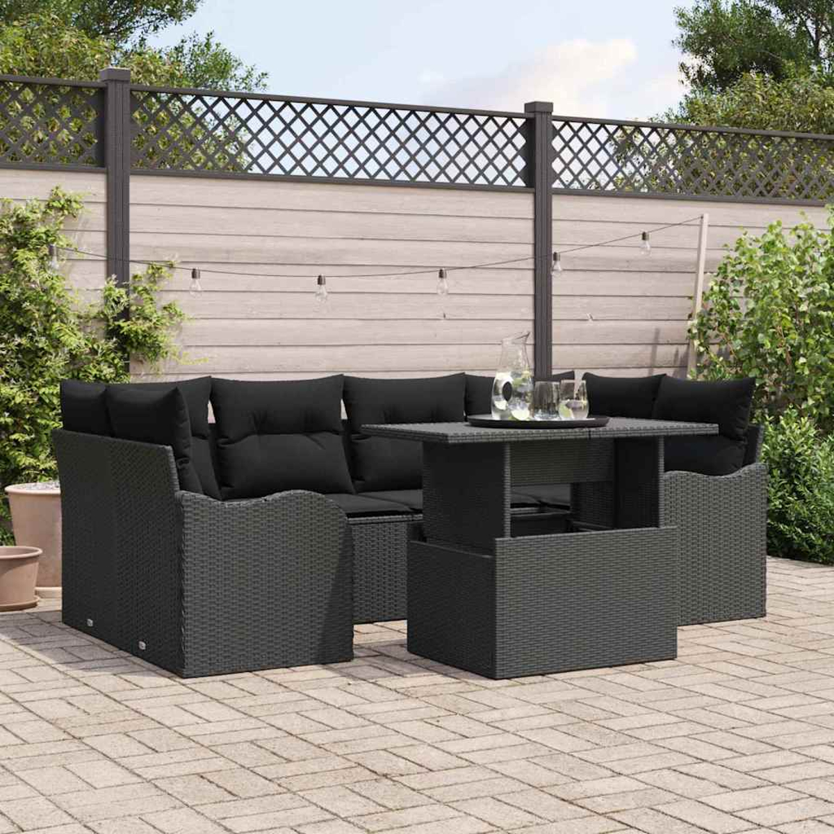Ein Outdoor-Set aus schwarzem Korbgeflecht mit schwarzen Kissen und einem Tisch mit einem Tablett mit Getränken.
