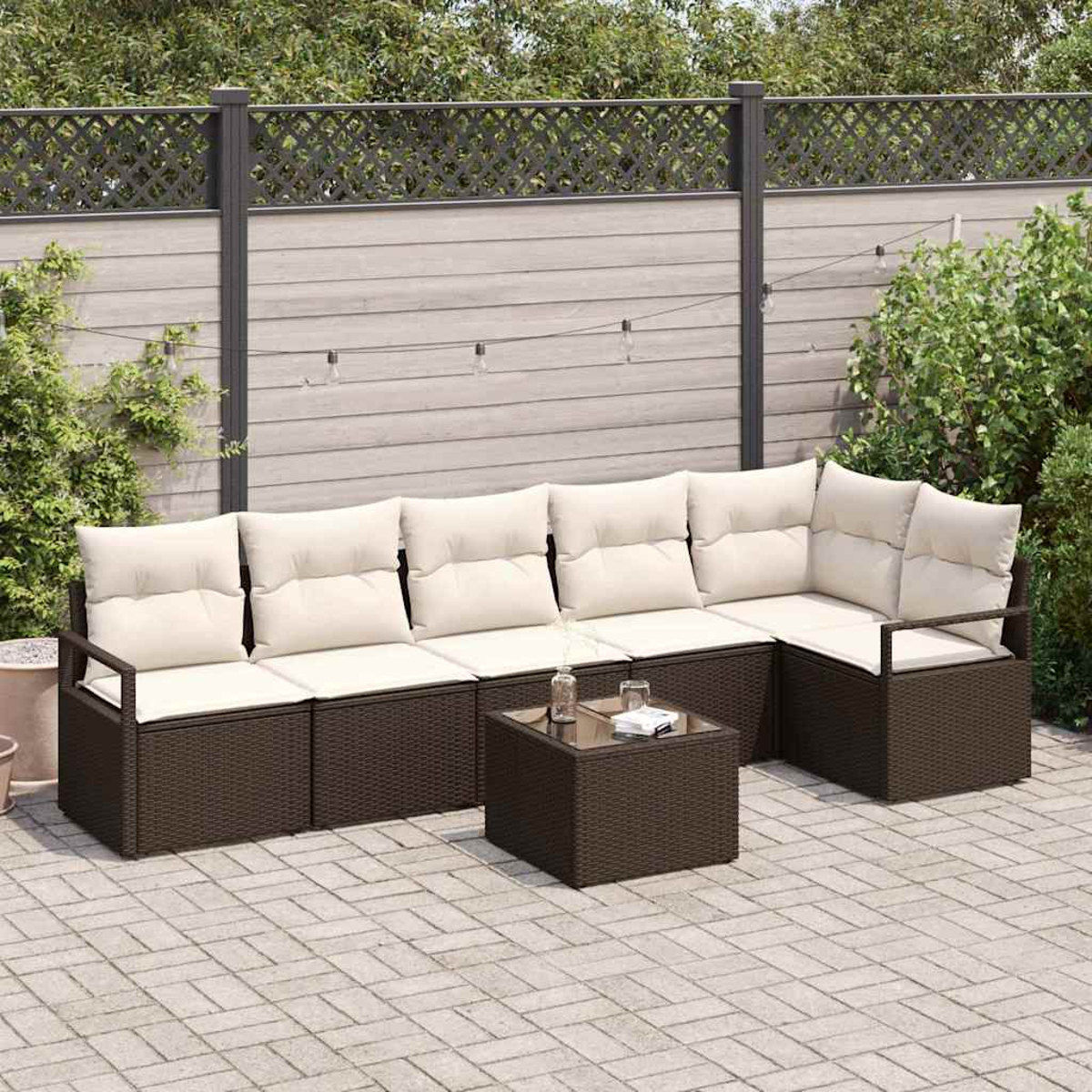 Outdoor-Ecksofa mit beigefarbenen Kissen und einem kleinen Tisch auf einer Backstein-Terrasse. Zaun und Pflanzen im Hintergrund.
