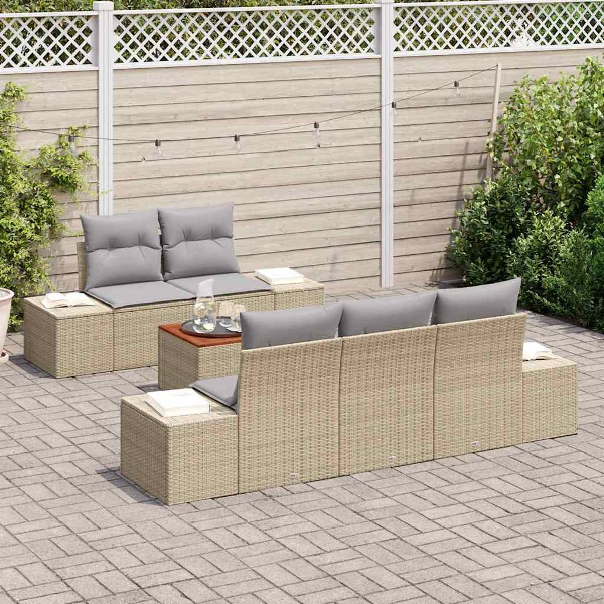 Gartenmöbel-Set aus Korbgeflecht mit grauen Kissen. Beinhaltet ein Sofa, zwei Stühle und einen kleinen Tisch auf einer Terrasse.