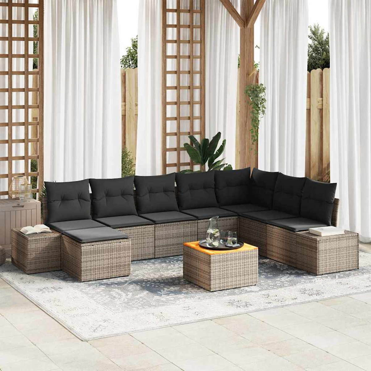 Gartenmöbel mit grauen Kissen. Enthält Sofa, Ottomane und Couchtisch. Weiße Vorhänge und hölzerne Gitter sichtbar.
