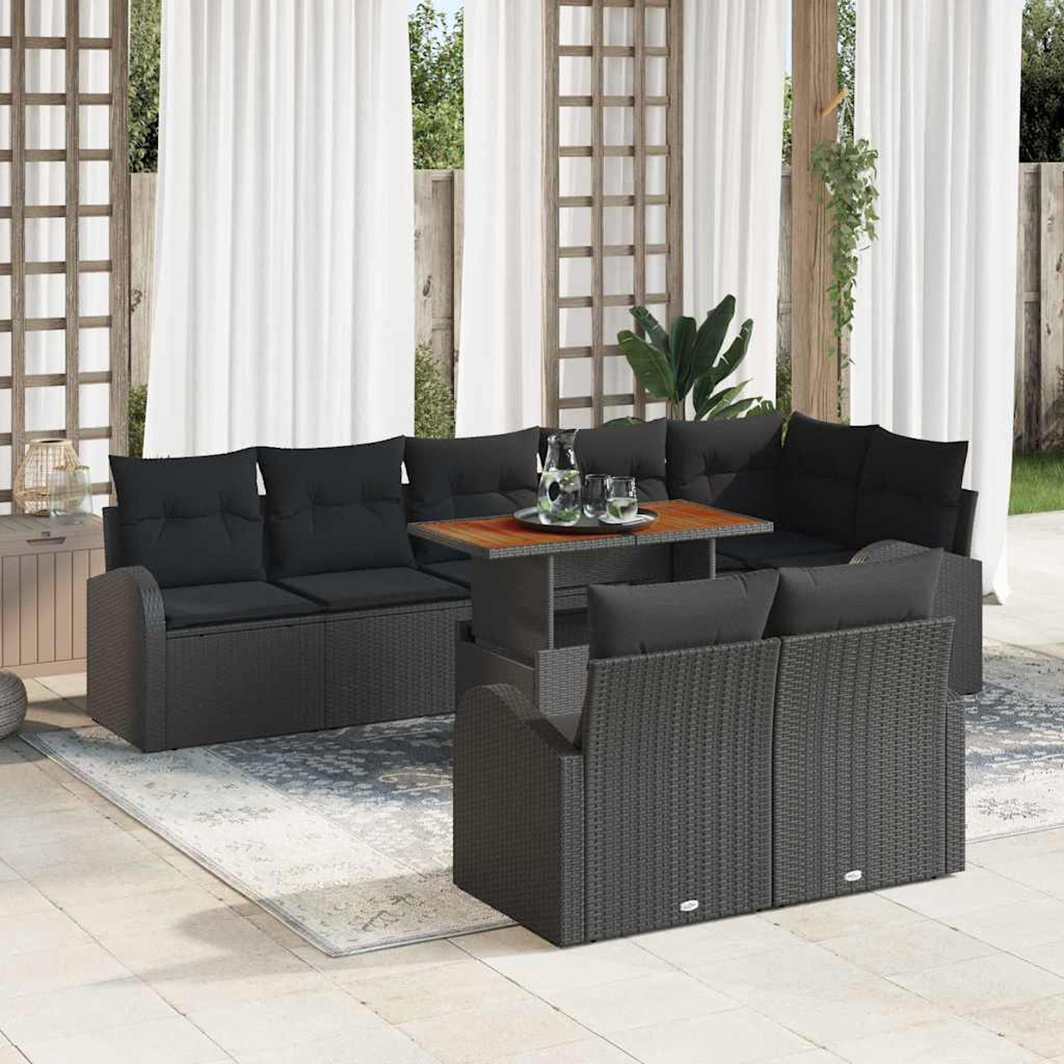 Sitzbereich im Freien mit dunklem Korb-Ecksofa, gepolsterten Sitzen und einem Holztisch auf einem hellen Teppich.