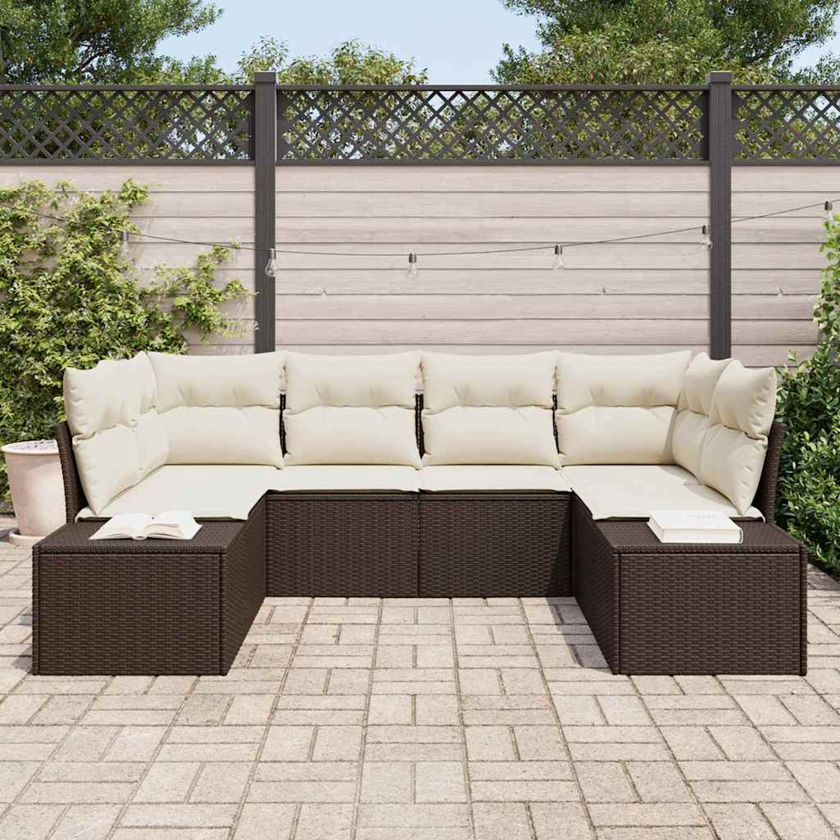 U-förmiges braunes Outdoor-Korbmöbel mit cremefarbenen Kissen, zwei Beistelltische mit Büchern, vor Holzzaun und Grün.