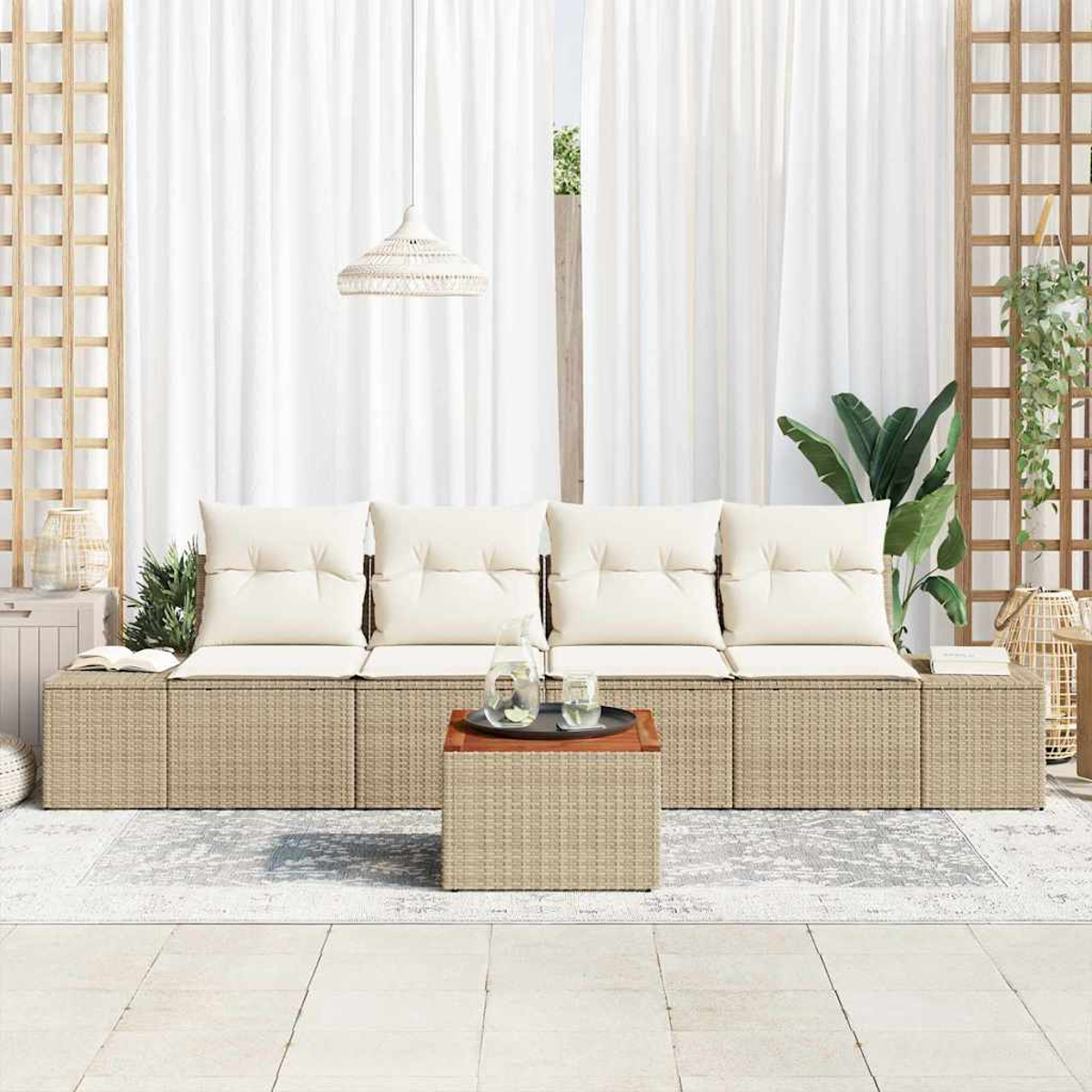 Außenbereich mit einem geflochtenen Sofa, cremefarbenen Kissen und einem Holztisch. Weiße Vorhänge und Pflanzen im Hintergrund.