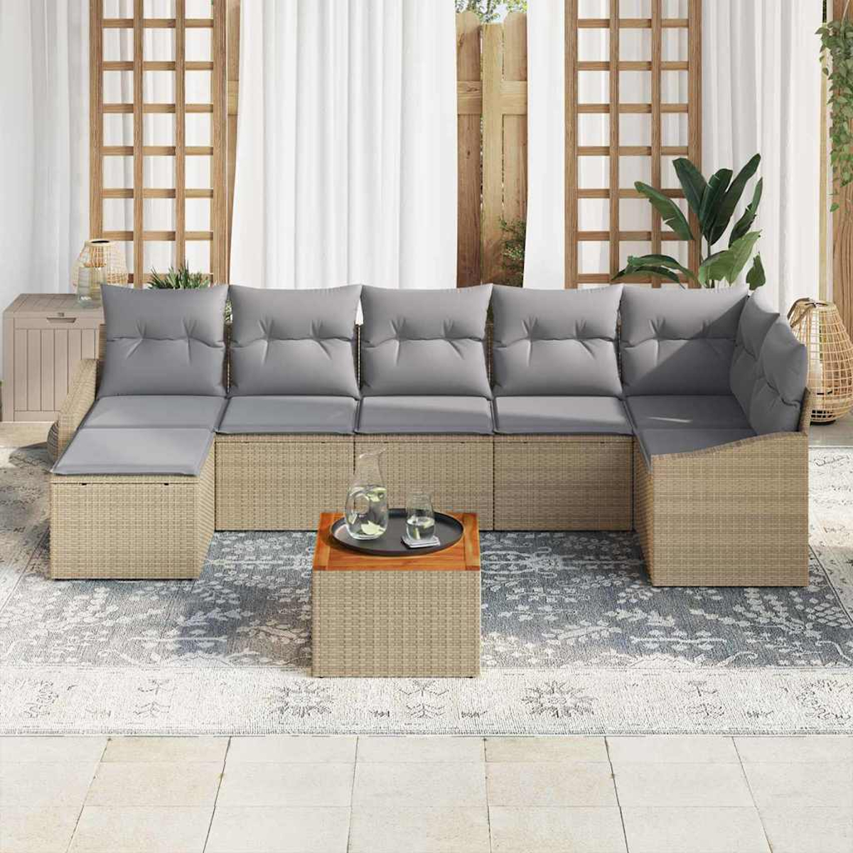 Outdoor-Ecksofa mit grauen Kissen, kleiner Holztisch mit Getränken. Beige Korbmöbel auf einem gemusterten Teppich, in der Nähe eines Fensters.