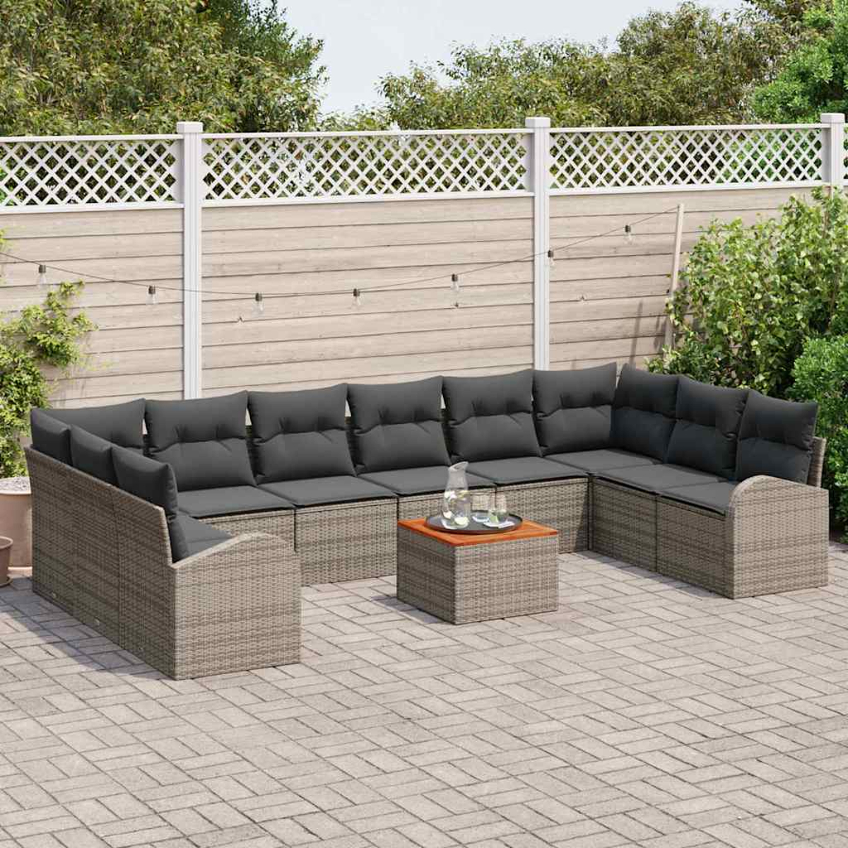 Un sofá seccional de mimbre gris para exteriores con cojines grises oscuros. Una mesita con vasos está en el patio.