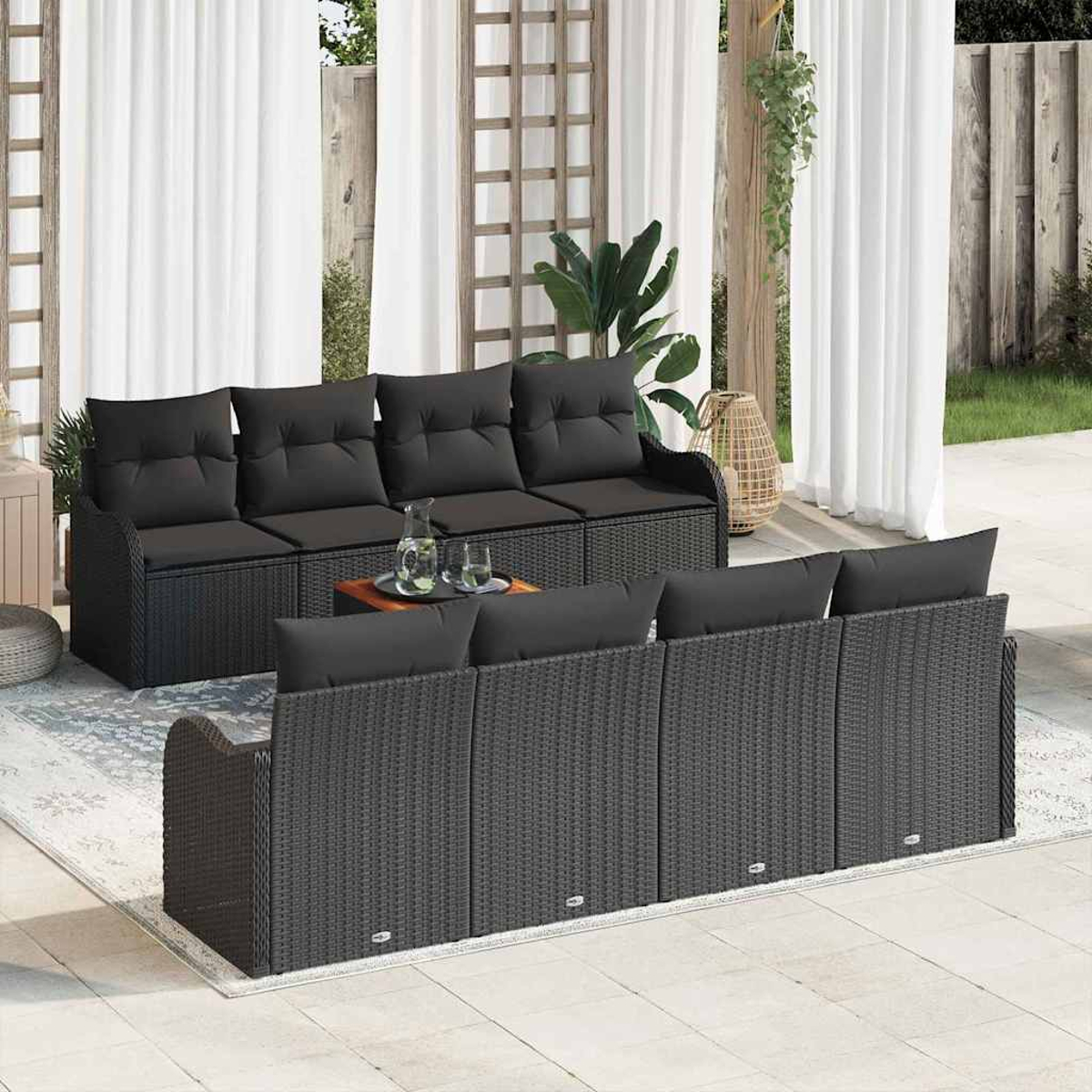 Outdoor-Terrassenset mit schwarzen Korbsesseln, Kissen und einem Tisch. Weiße Vorhänge im Hintergrund.