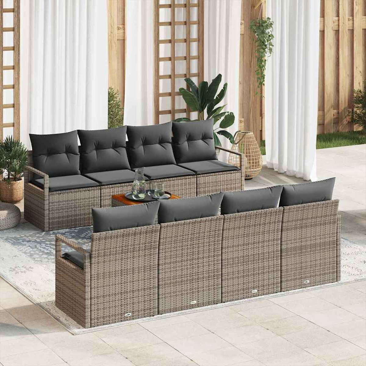 Terrassenmöbel mit grauen Kissen. Möbel im Korbstil auf einer Terrasse, Vorhänge, Pflanzen und ein kleiner Tisch. Helle, sonnige Szene.
