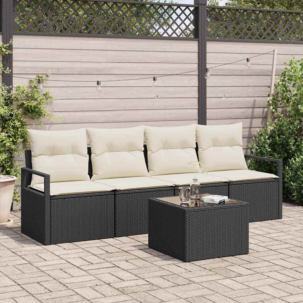 Asientos al aire libre con cojines crema y una mesa cuadrada. Muebles negros tejidos en un patio, con una valla y luces de cadena en el fondo.