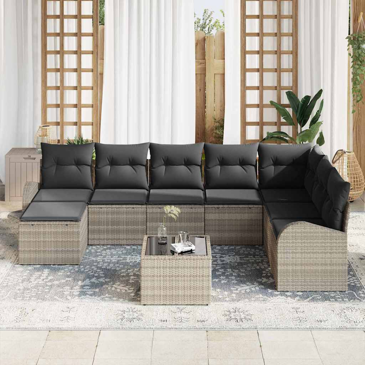 Outdoor-Ecksofa mit grauen Kissen und einem kleinen Tisch auf einem gemusterten Teppich, in der Nähe eines Fensters.