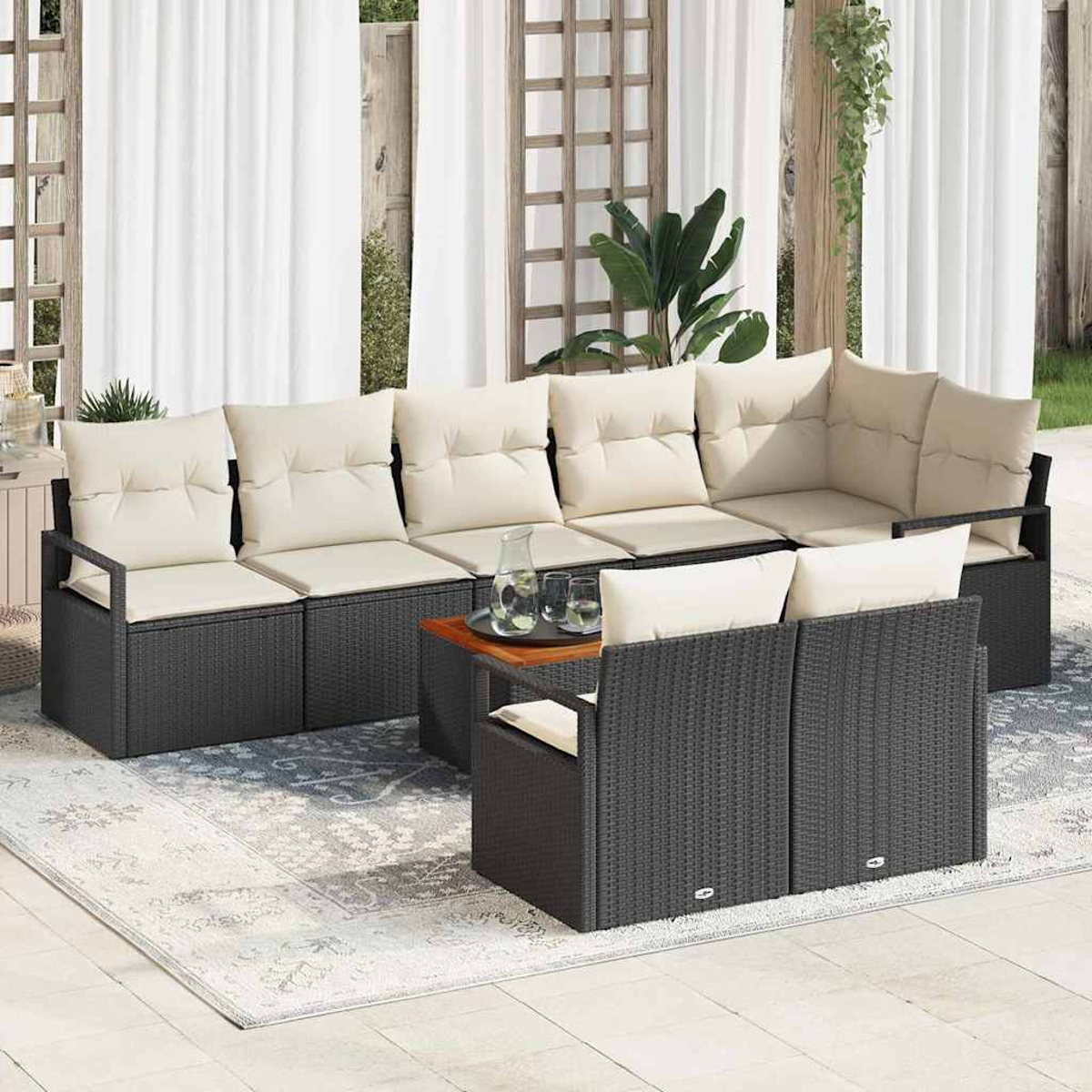 Outdoor-Ecksofa mit cremefarbenen Kissen auf einem gemusterten Teppich. Ein kleiner Tisch mit Gläsern und einer Kanne. Weiße Vorhänge im Hintergrund.