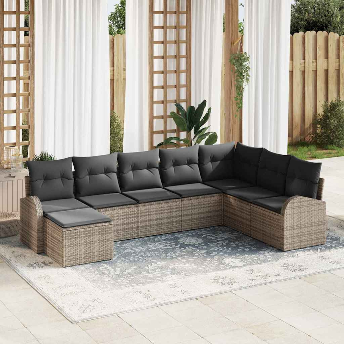 Ein Ecksofa im Freien mit grauen Kissen steht auf einem gemusterten Teppich. Weiße Vorhänge und Holzgitter sind im Hintergrund.