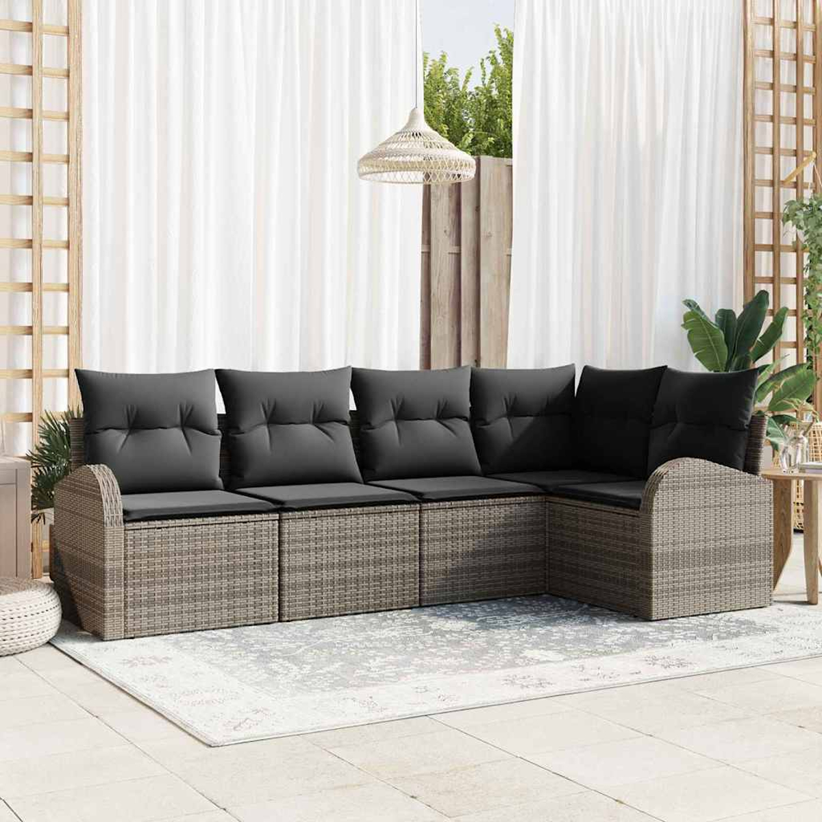 Ein Ecksofa im Freien mit grauen Kissen. Weiße Vorhänge, eine gewebte Leuchte und ein dekoratives Gitter sind im Hintergrund sichtbar.