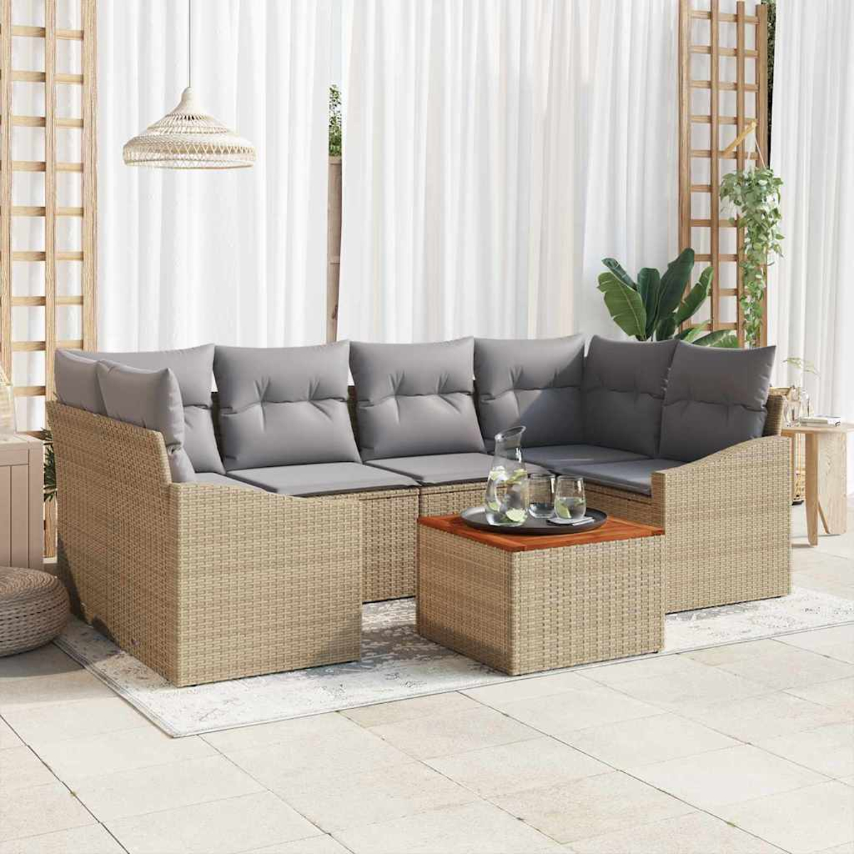 Outdoor-Ecksofa mit grauen Kissen, Korbgeflechtrahmen und einem Holztisch. Weiße Vorhänge und Pflanzen im Hintergrund.