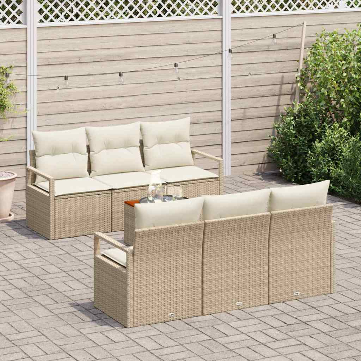 Outdoor-Korbmöbel-Set mit beigefarbenen Kissen auf einer Terrasse. Enthält ein Sofa und zwei Stühle mit einem kleinen Tisch.
