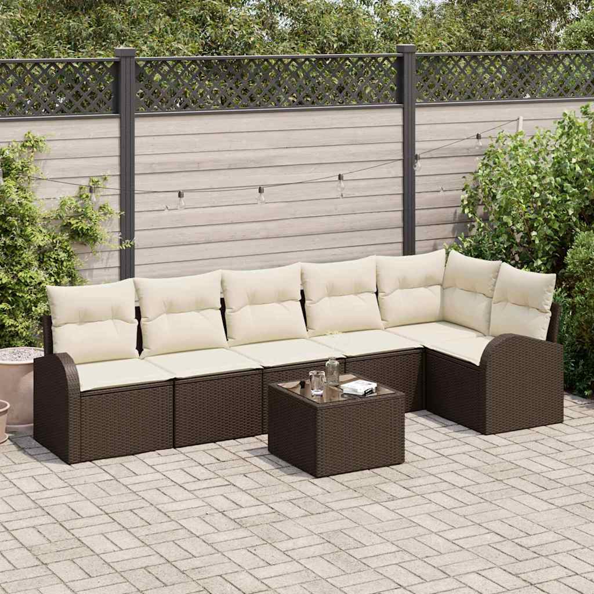 Garten-Sitzgruppe mit braunen Korbflechtrahmen, cremefarbenen Kissen und einem kleinen Tisch auf einer gepflasterten Terrasse.