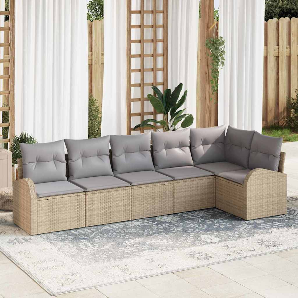 Outdoor-Ecksofa mit grauen Kissen. Beigefarbene Webbasis auf einem gemusterten Teppich. Im Hintergrund weiße Vorhänge und Holzstrukturen.