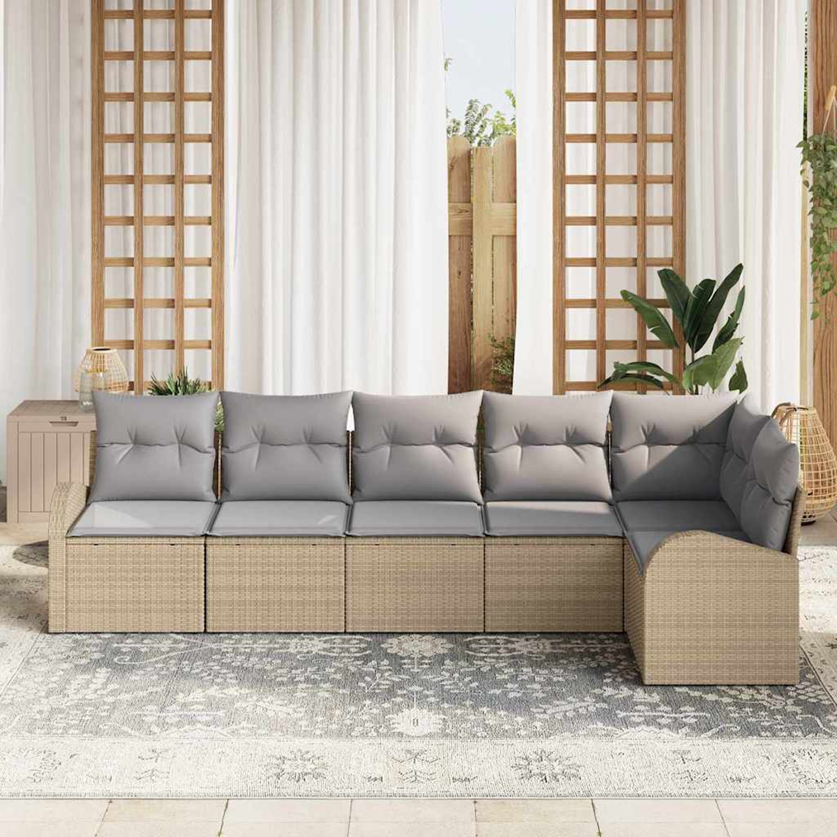 Ein Ecksofa im Freien mit grauen Kissen auf einem gemusterten Teppich. Holzgitter, weiße Vorhänge und Pflanzen im Hintergrund.