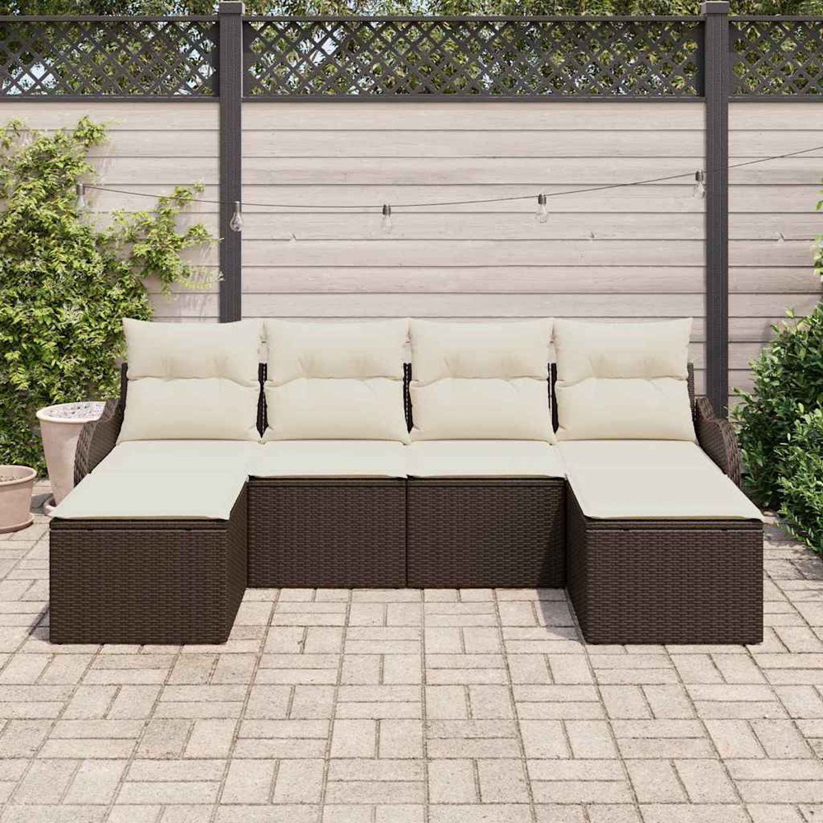 Un sofá seccional al aire libre con cojines beige. Es de mimbre marrón con una valla de madera de color claro al fondo.