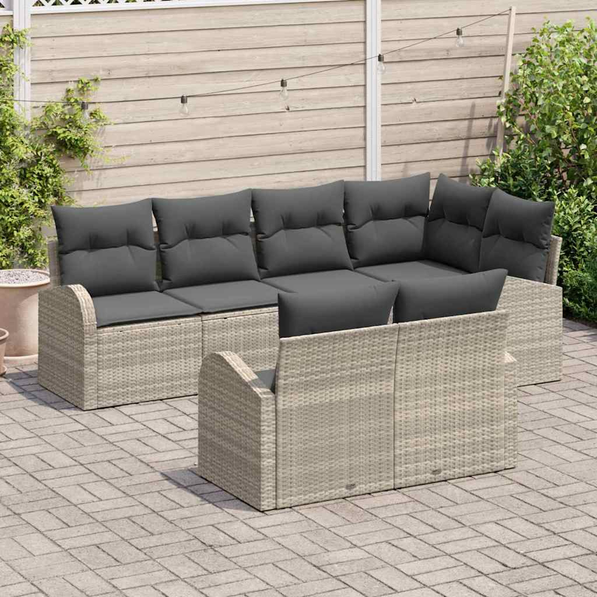 Gartenmöbel-Set mit grauen Kissen. Beige Korbsessel und -stühle sind auf einer Ziegelterrasse angeordnet. Holzzaun im Hintergrund.