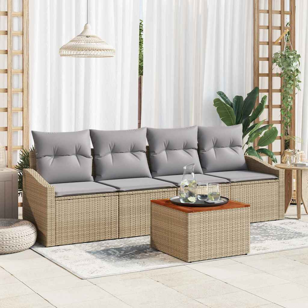 Ein Rattansofa mit grauen Kissen, ein Couchtisch mit Getränken und ein weißer Vorhang im Hintergrund auf einer Terrasse.