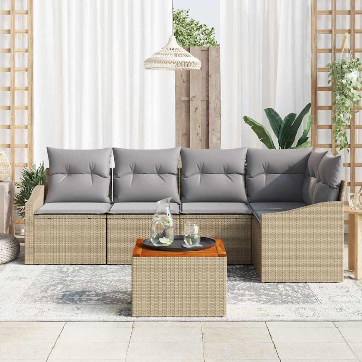 Outdoor-Sitzgruppe mit grauen Kissen und Rattangestell. Ein Holztisch mit Tablett und Glas Wasser.