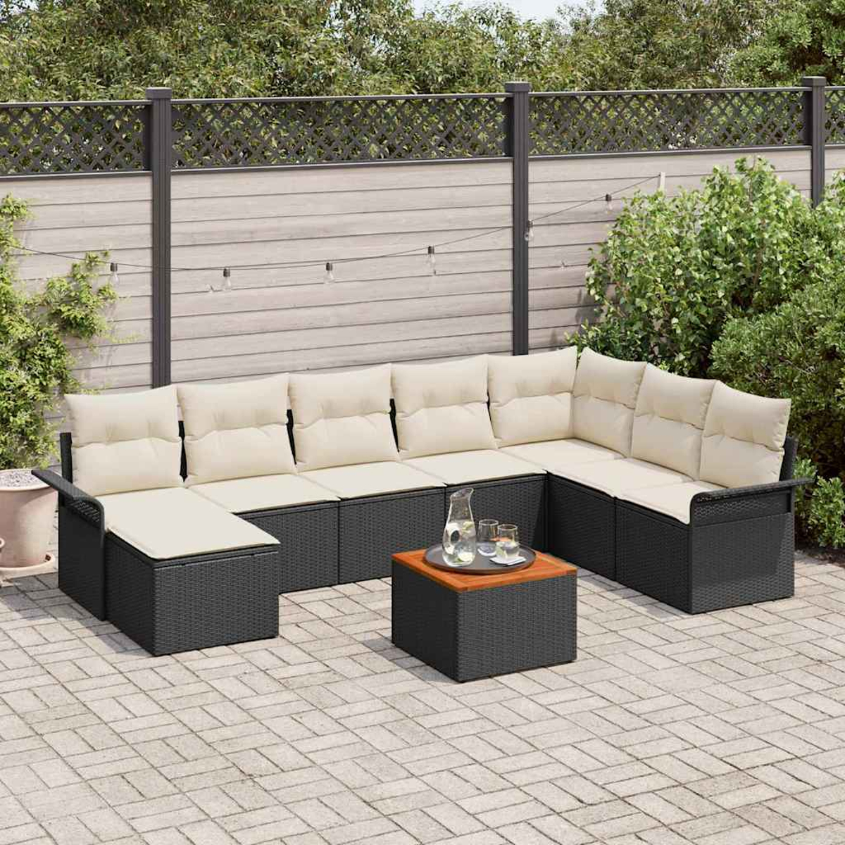 Ein Ecksofa im Freien mit cremefarbenen Kissen und einem kleinen Tisch mit Getränken. Der Hintergrund umfasst einen Zaun und Grün.