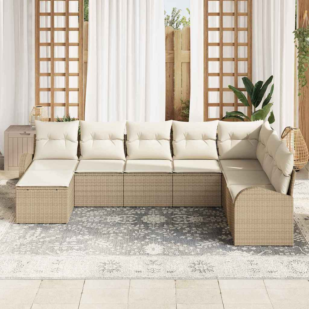 Sofá seccional exterior con cojines beige. Base de ratán en un patio con alfombra. El fondo incluye cortinas, paneles de madera y plantas.