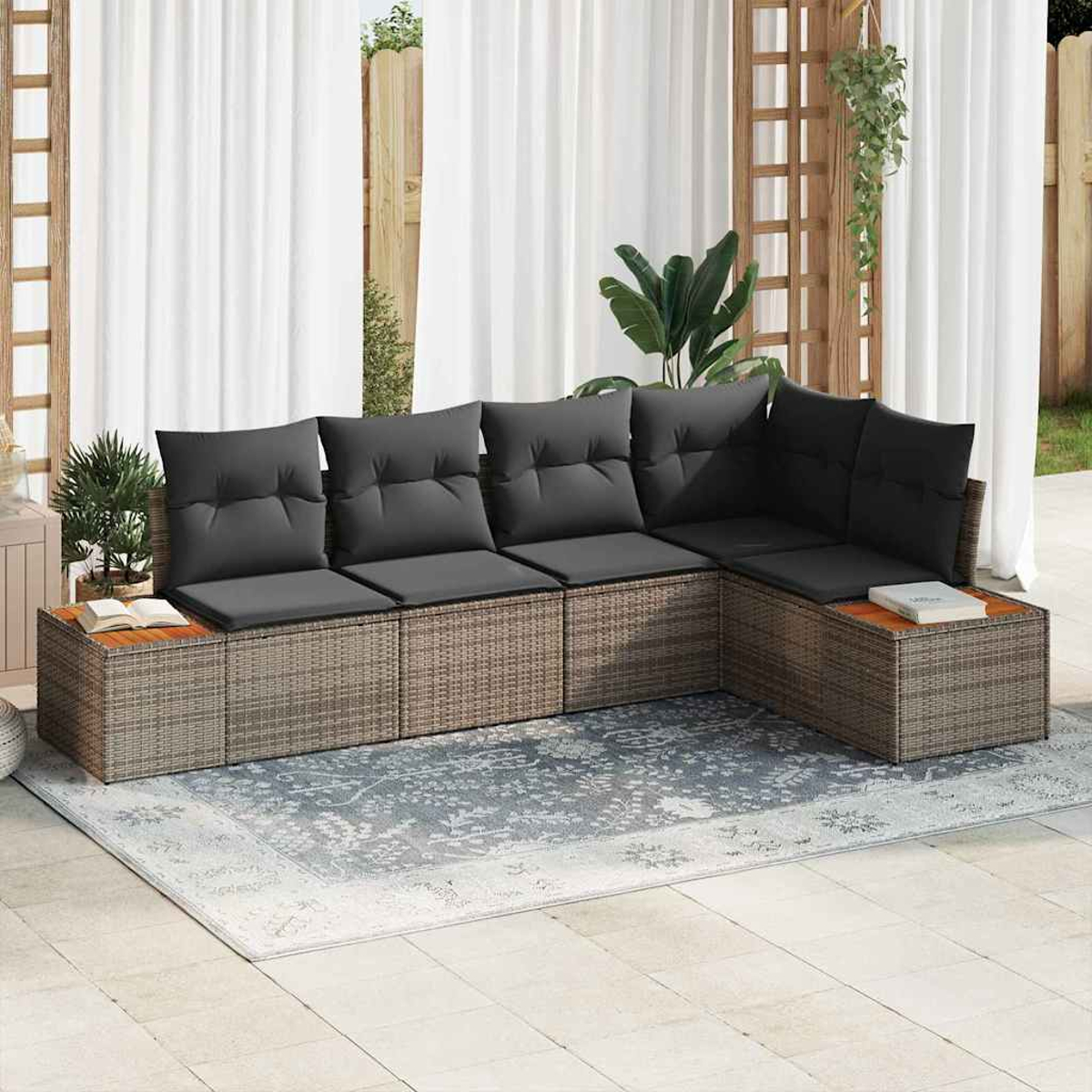 Ein Ecksofa mit grauen Kissen steht auf einem Teppich. Weiße Vorhänge und ein Holzgitter sind im Hintergrund.