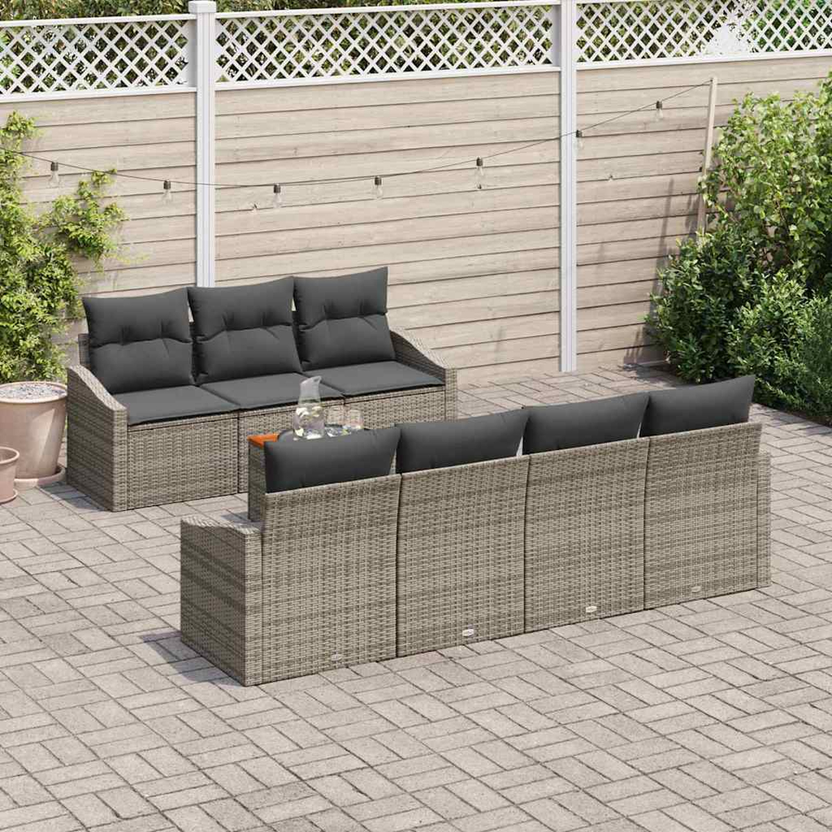 Outdoor-Sitzbereich. Zwei graue Korbsessel mit dunkelgrauen Kissen, ein kleiner Tisch und ein hellfarbener Holzzaun im Hintergrund.