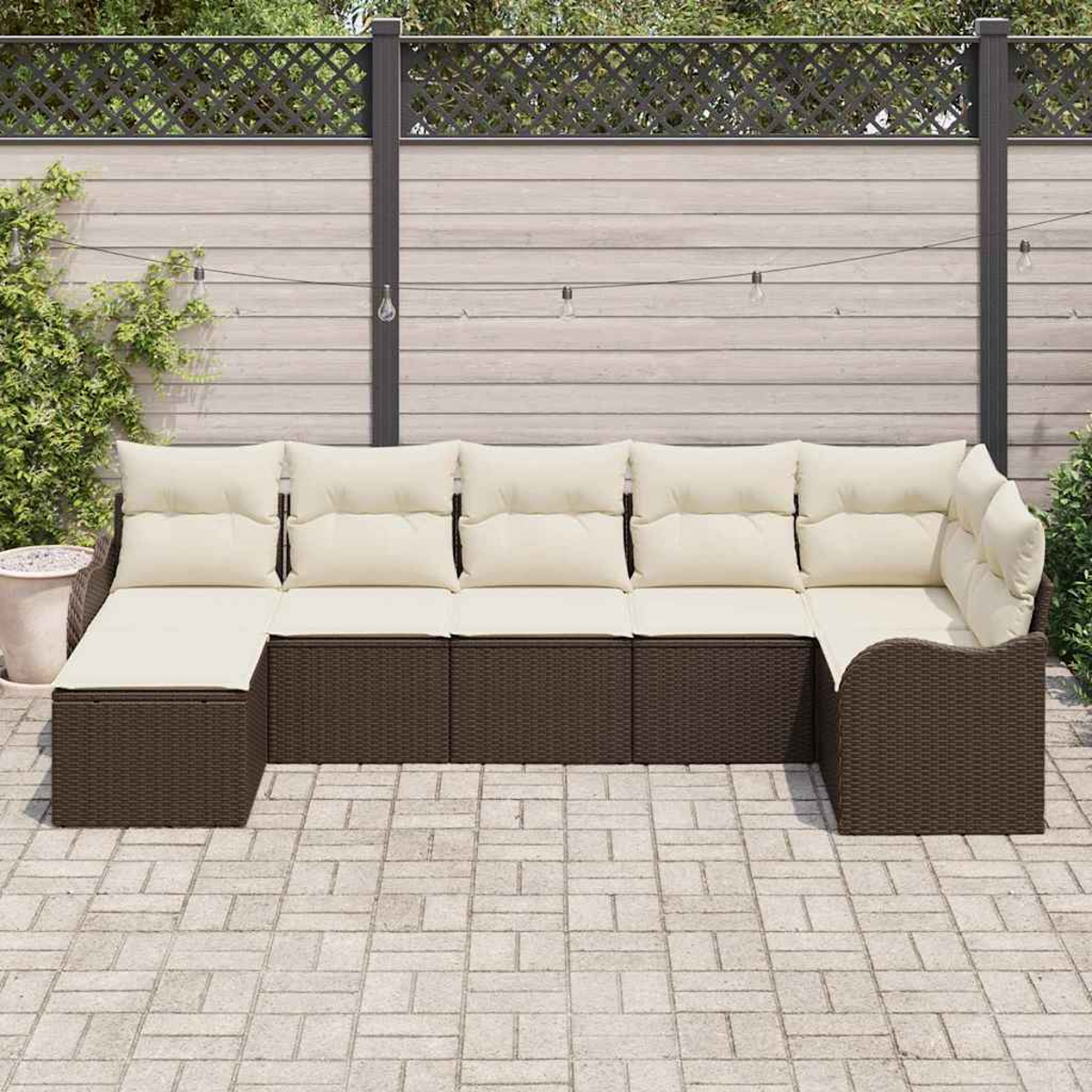 Outdoor-Ecksofa mit cremefarbenen Kissen und braunem Korbgewebe auf einer Terrasse. Ein Holzzaun und Grünzeug im Hintergrund.