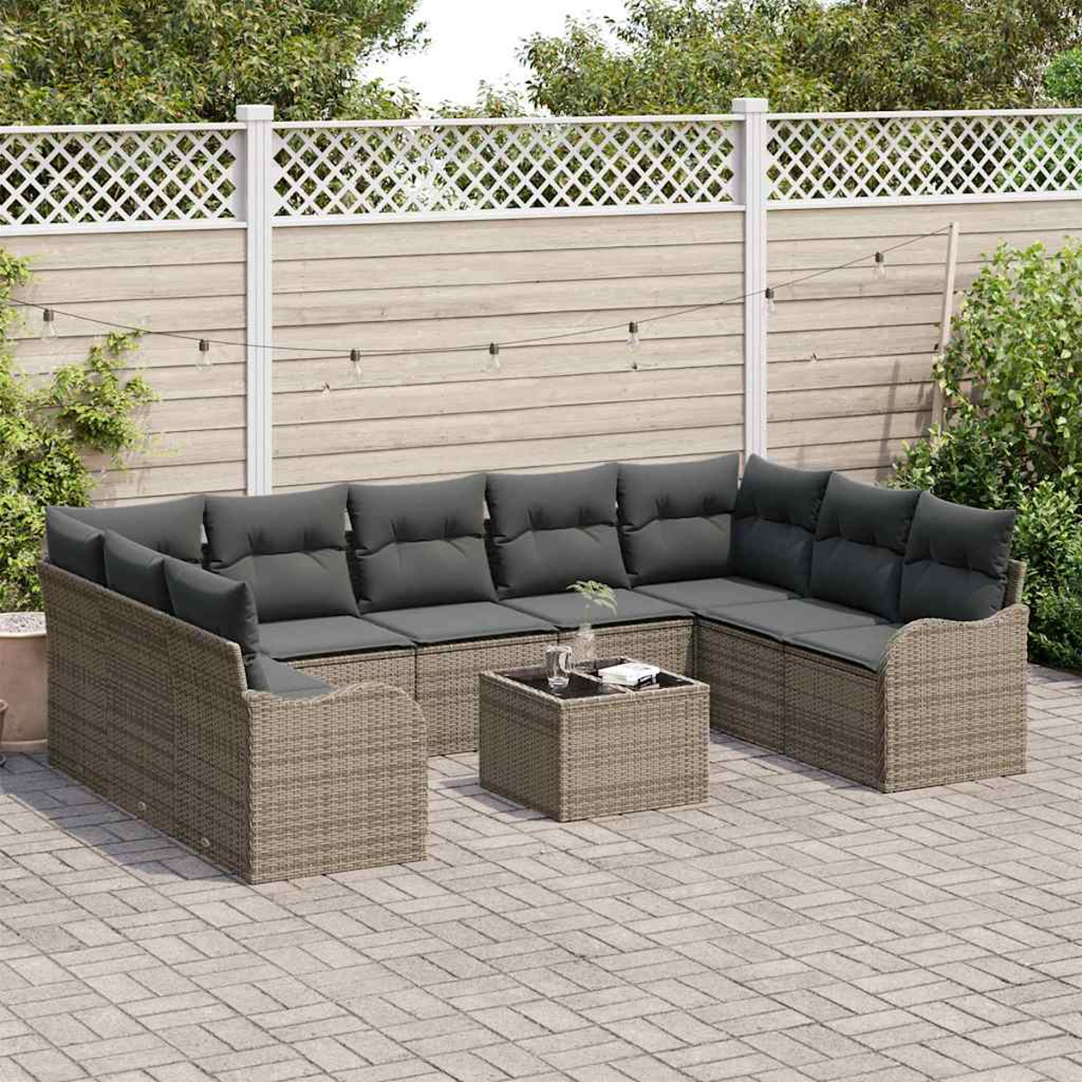 Ein Outdoor-Terrassenset mit grauen Kissen auf einem hellbraunen Korbgeweberahmen, einem kleinen Tisch und einem weißen Zaun im Hintergrund.