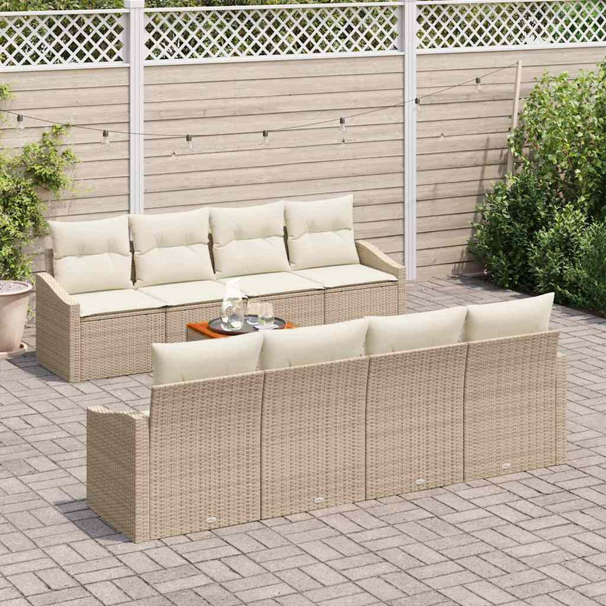 Szene einer Außenterrasse mit zwei Rattansofas mit cremefarbenen Kissen, einem kleinen Tisch und einem Holzzaun im Hintergrund mit Pflanzen.