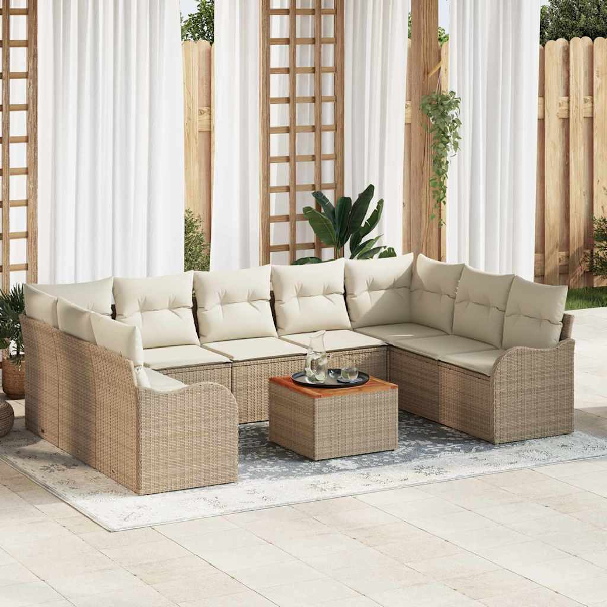Una zona de estar al aire libre con un sofá seccional beige y una mesa de centro a juego, sobre una alfombra estampada. Cortinas blancas y valla de madera.