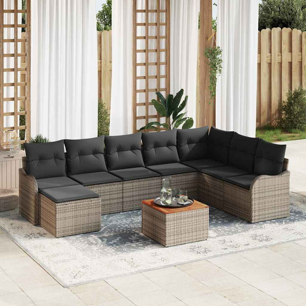 Outdoor-Ecksofa mit grauen Kissen, einem kleinen Tisch mit Getränken und einem Teppich. Weiße Vorhänge und ein Holzzaun sind im Hintergrund.