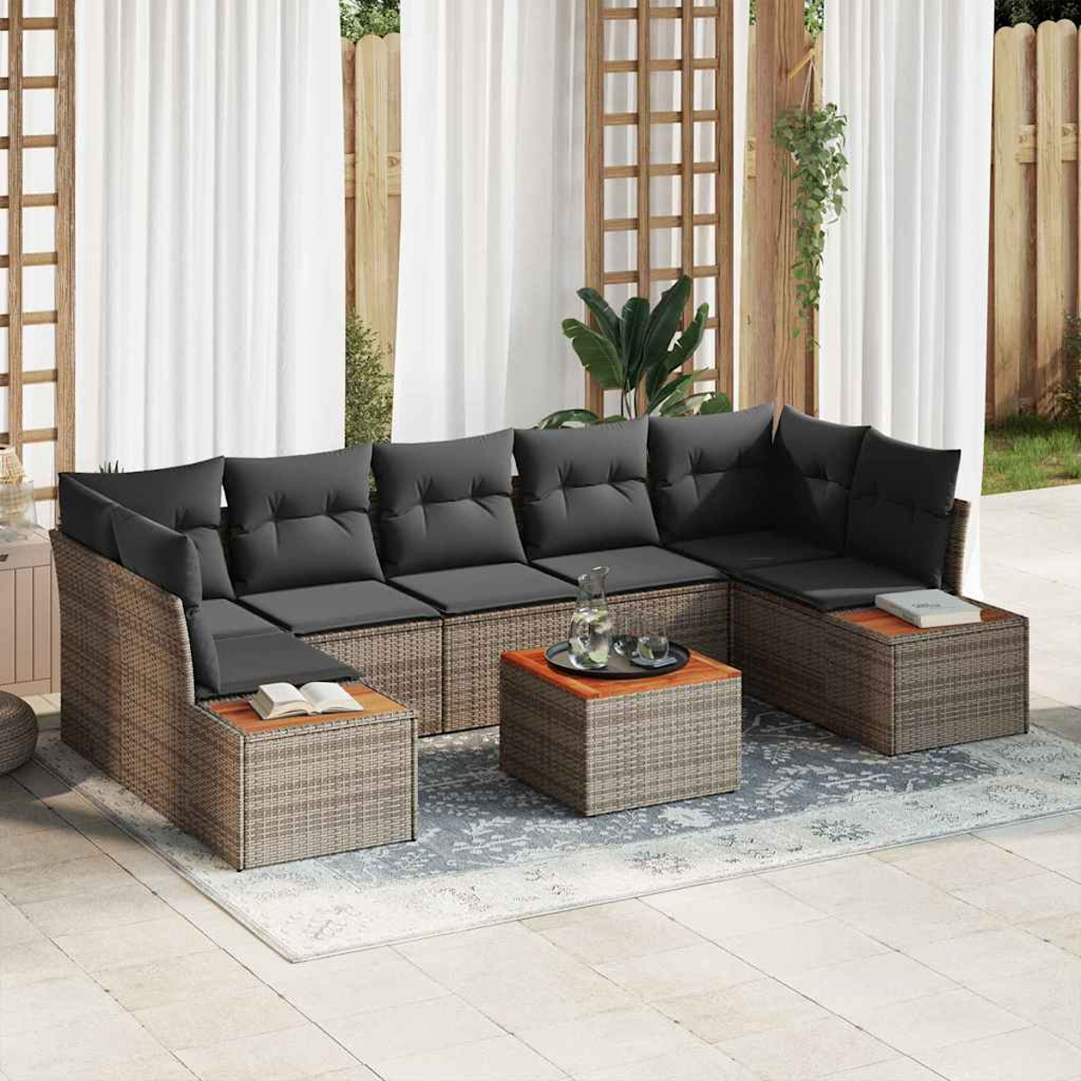 Outdoor-Ecksofa mit grauen Kissen, Holzakzenten und einem Couchtisch auf einem gemusterten Teppich vor Vorhängen und einem Zaun.