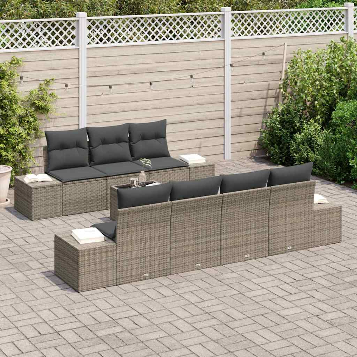 Gartenmöbel-Set. Graue Kissen auf Korbsesseln. Weißer Gitterzaun, Lichterketten und grüne Sträucher im Hintergrund.