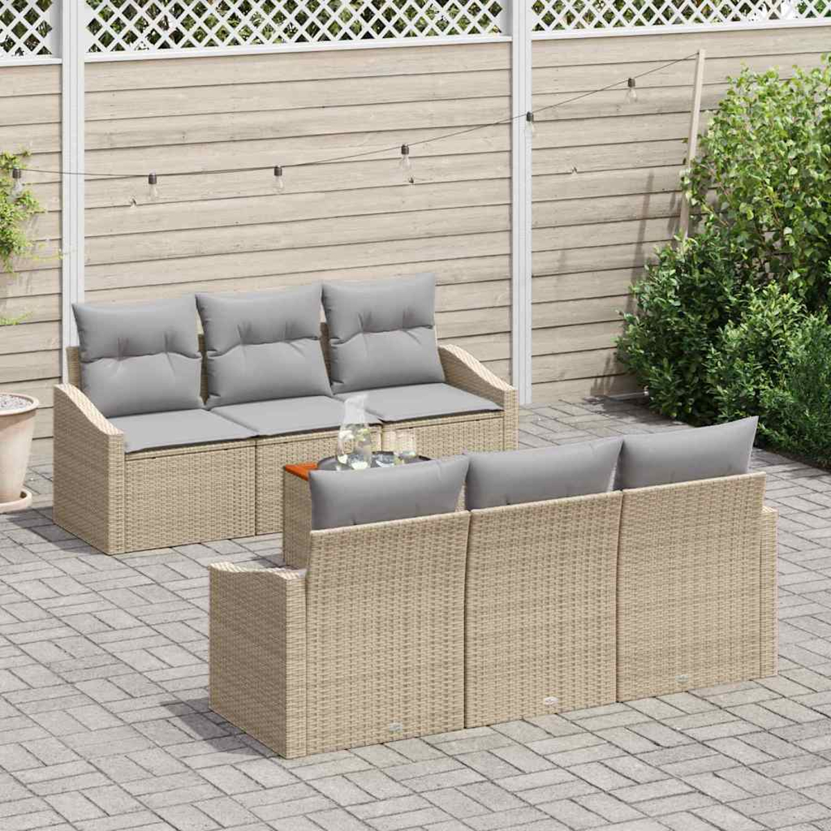 Gartenmöbel-Set mit grauen Kissen. Zwei Sofas, ein Tisch mit Gläsern und ein Holzzaun im Hintergrund. Gepflasterte Terrasse.