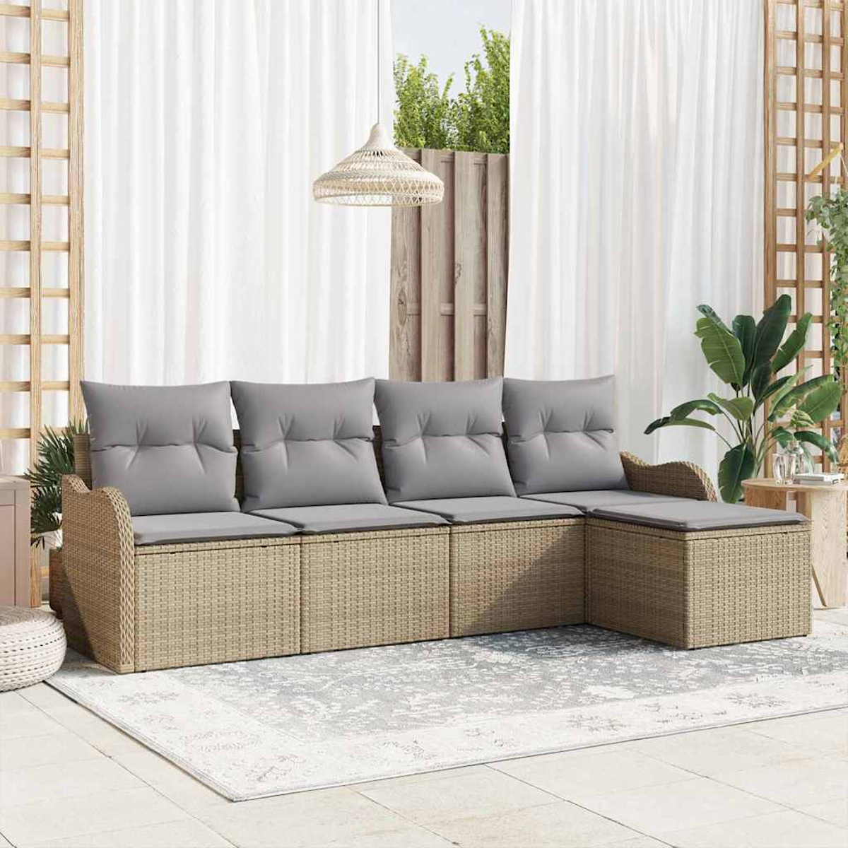 Outdoor-Rattansofa mit grauen Kissen auf einem gemusterten Teppich. Weiße Vorhänge und eine Hängelampe im Hintergrund.