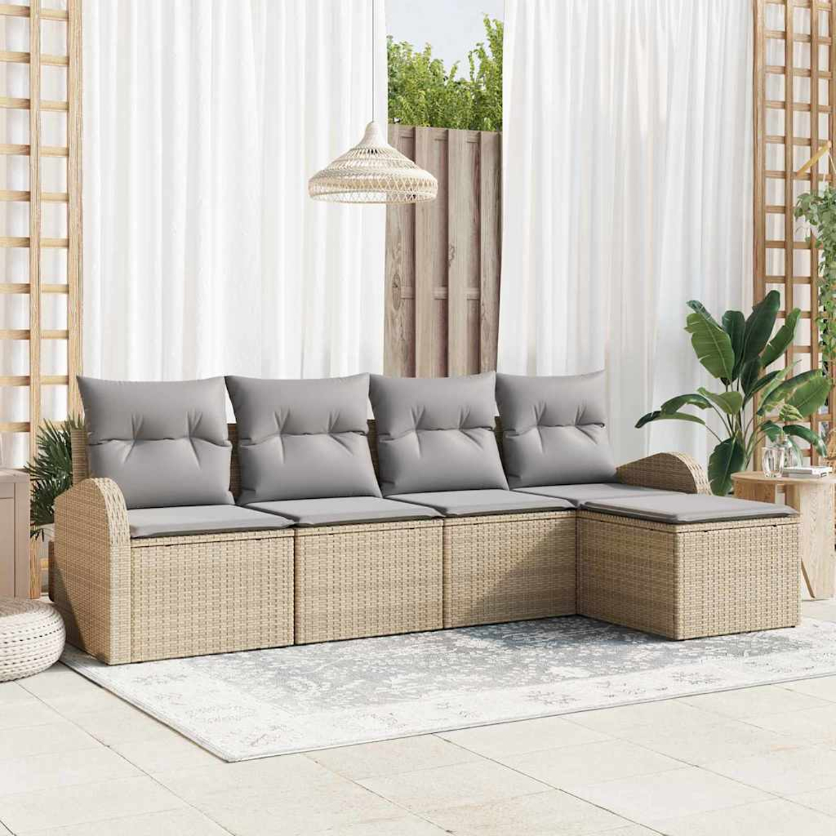Geflochtenes Outdoor-Sofa mit grauen Kissen auf einem grauen Teppich, weißen Vorhängen im Hintergrund und einer Pendelleuchte.
