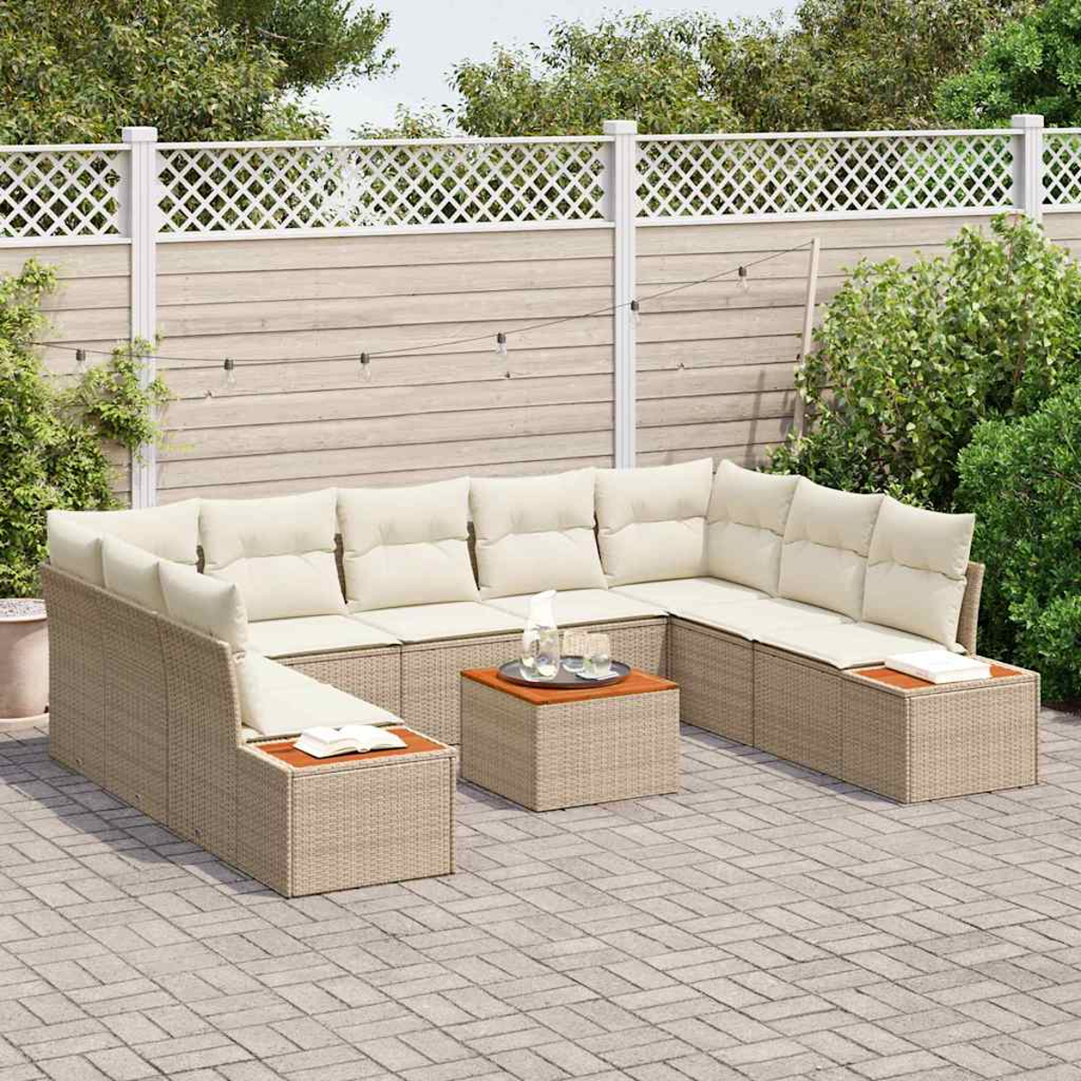 Sofá seccional exterior con cojines beige y dos mesas pequeñas en un patio de ladrillos. Valla blanca y plantas verdes al fondo.